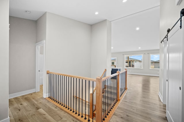 hall featuring recessed lighting, wood finished floors, baseboards, and a barn door