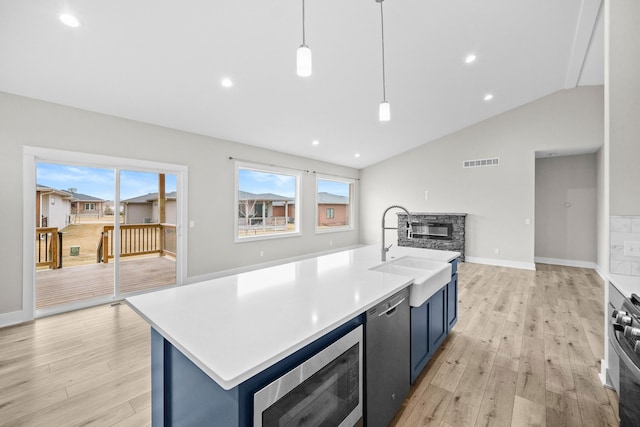 kitchen featuring blue cabinetry, visible vents, open floor plan, a sink, and a stone fireplace