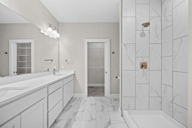 full bathroom featuring marble finish floor, tiled shower, a sink, and baseboards