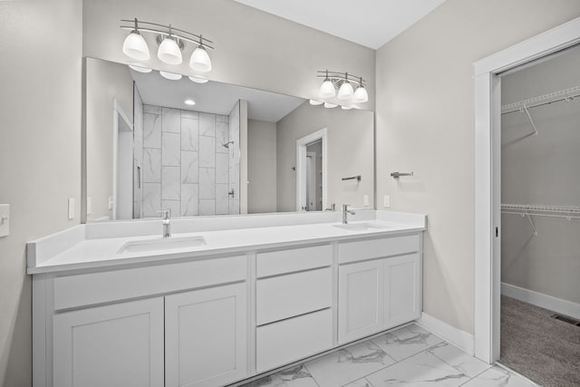 bathroom featuring marble finish floor, visible vents, a tile shower, and a sink