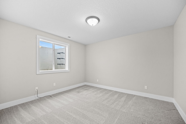 unfurnished room with a textured ceiling, carpet floors, visible vents, and baseboards