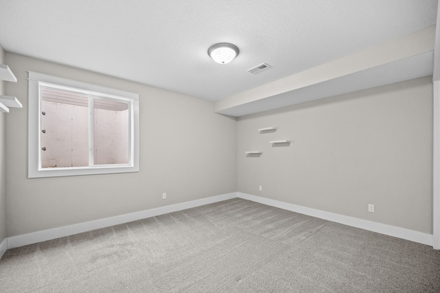 carpeted spare room with a textured ceiling, visible vents, and baseboards