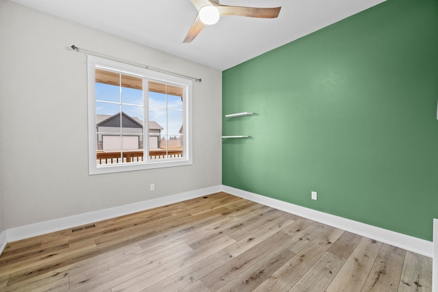 spare room with a ceiling fan, baseboards, visible vents, and wood finished floors