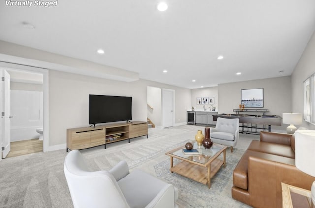 living room featuring recessed lighting, baseboards, bar area, and light carpet