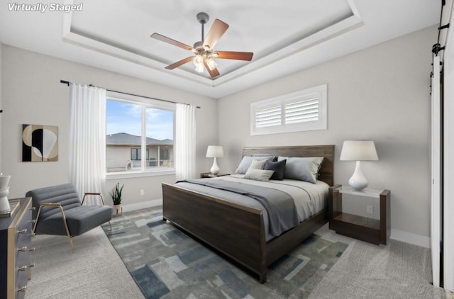 bedroom featuring a tray ceiling, baseboards, and a barn door