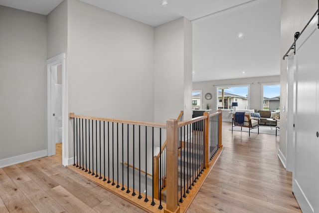 hallway featuring wood-type flooring, recessed lighting, an upstairs landing, and a barn door