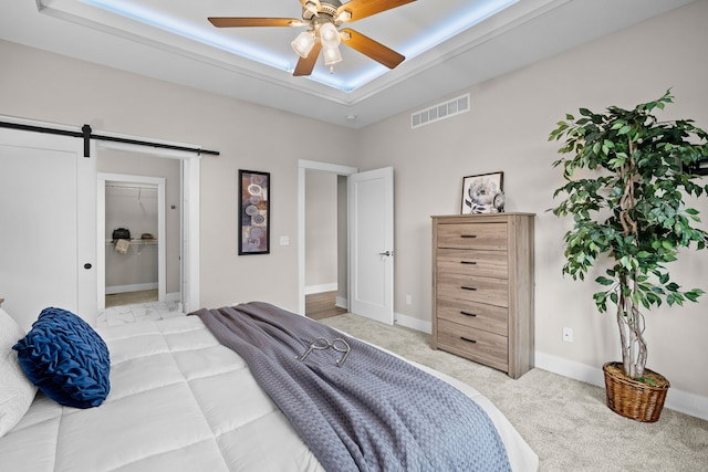 bedroom with light colored carpet, a barn door, a ceiling fan, baseboards, and visible vents
