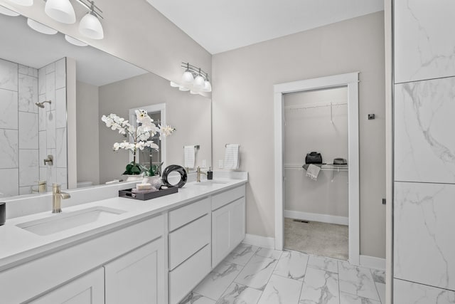 full bathroom featuring double vanity, a tile shower, a sink, and marble finish floor