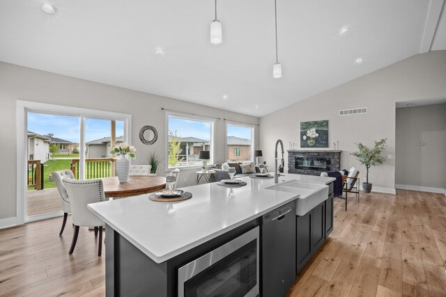 kitchen with a sink, light wood-style flooring, appliances with stainless steel finishes, and open floor plan