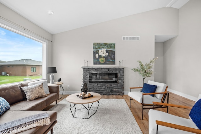 living room with visible vents, wood finished floors, a fireplace, baseboards, and high vaulted ceiling