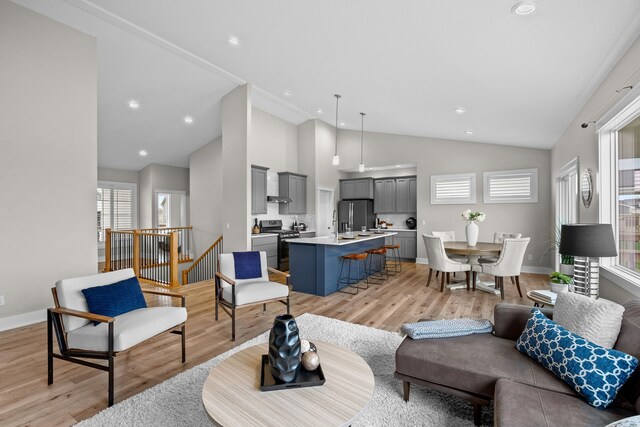 living room featuring recessed lighting, baseboards, high vaulted ceiling, and light wood-style flooring