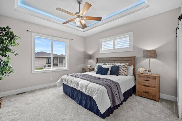 carpeted bedroom featuring a raised ceiling, baseboards, and visible vents