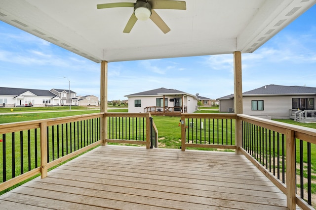 wooden deck with a residential view, a ceiling fan, and a yard