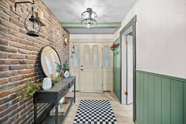 foyer entrance featuring light hardwood / wood-style floors, a textured ceiling, and brick wall