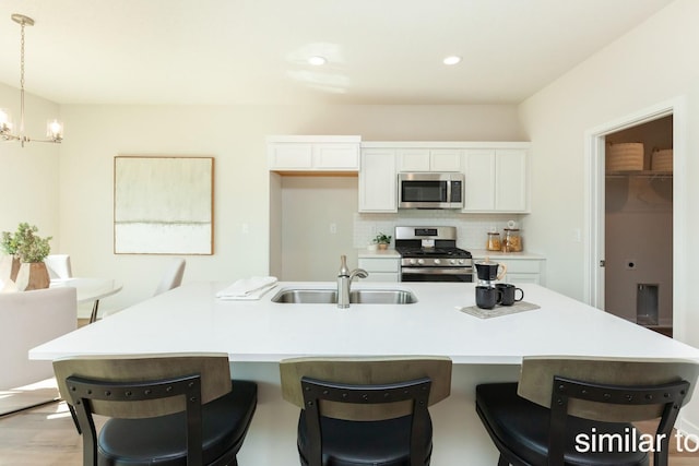 kitchen with decorative backsplash, white cabinets, stainless steel appliances, and a sink