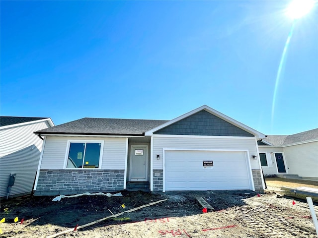 view of front of property with stone siding, a garage, and roof with shingles