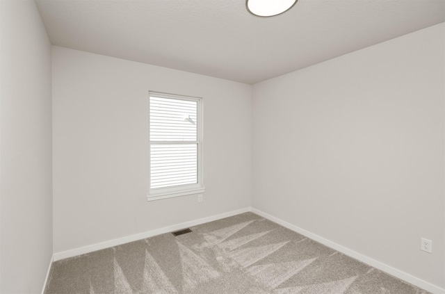 spare room with visible vents, baseboards, and carpet flooring