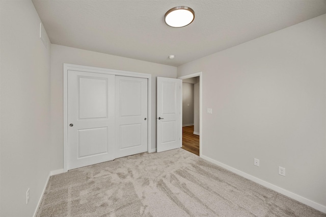 unfurnished bedroom with baseboards, carpet floors, and a closet
