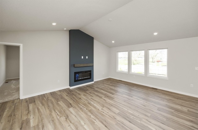 unfurnished living room with baseboards, recessed lighting, lofted ceiling, wood finished floors, and a fireplace