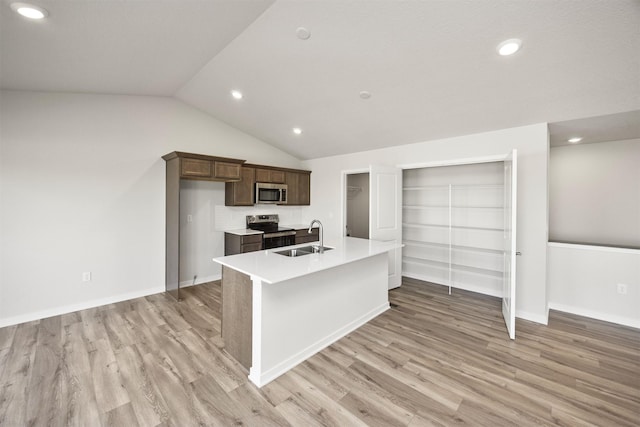 kitchen with lofted ceiling, stainless steel appliances, light wood finished floors, and a sink