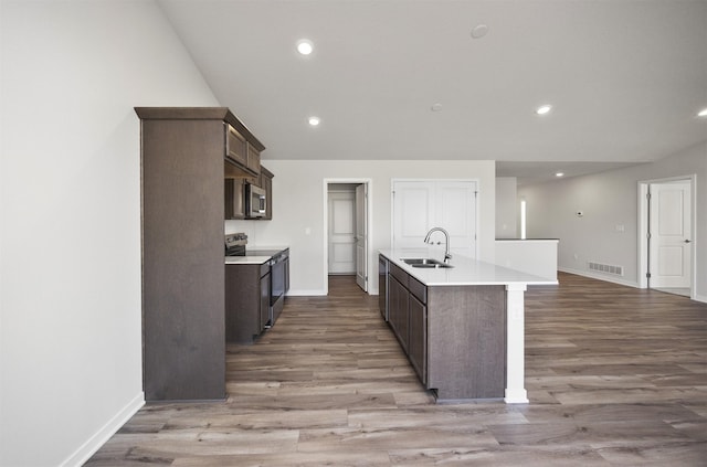 kitchen featuring dark brown cabinets, stainless steel appliances, visible vents, and a sink
