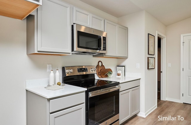 kitchen with stainless steel appliances, white cabinets, and light hardwood / wood-style floors