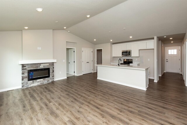 1099 NE 64th Ave, Des Moines, IA 50313 - unfurnished living room with lofted ceiling, baseboards, wood finished floors, recessed lighting, and a stone fireplace