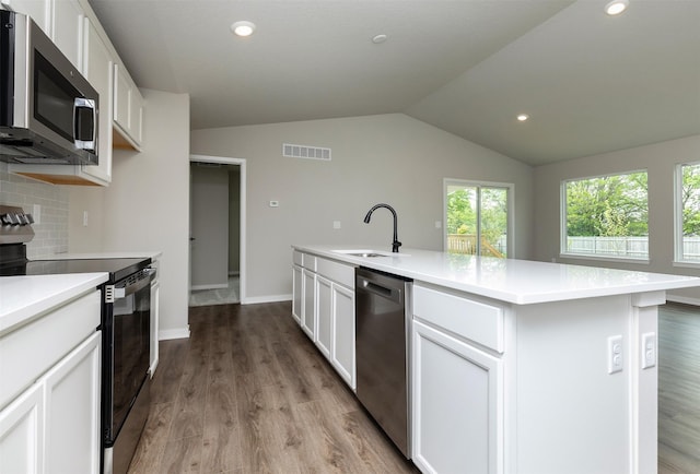 1099 NE 64th Ave, Des Moines, IA 50313 - kitchen featuring appliances with stainless steel finishes, a sink, vaulted ceiling, healthy amount of natural light, and white cabinets