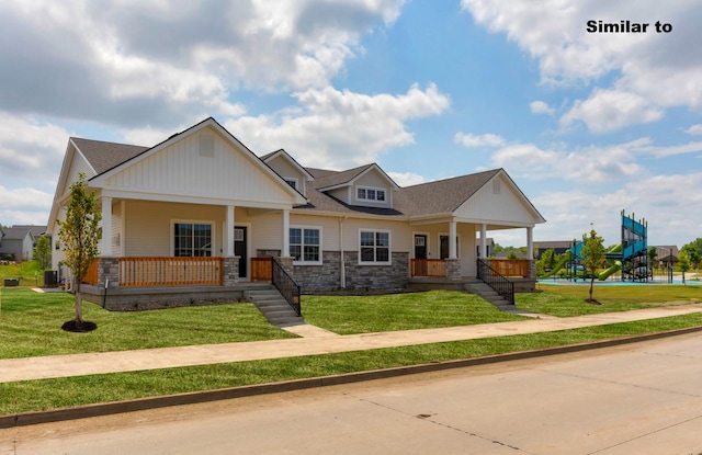 view of front of home with covered porch, stone siding, a front lawn, and a playground