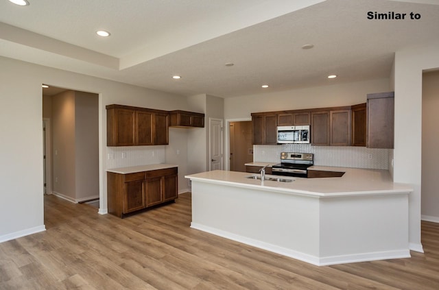 kitchen with stainless steel appliances, light wood-type flooring, light countertops, and a sink