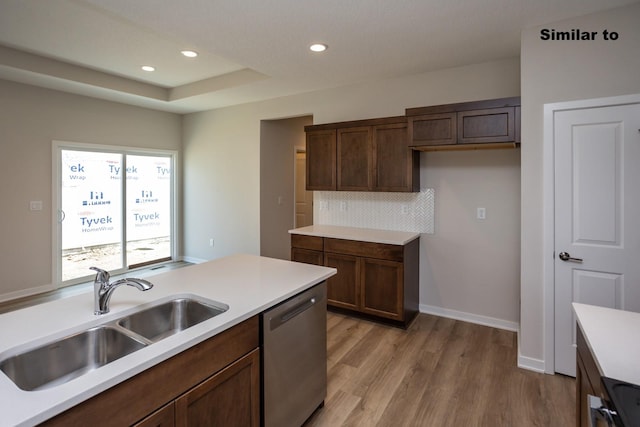 kitchen featuring a sink, light wood-style floors, light countertops, stainless steel dishwasher, and decorative backsplash