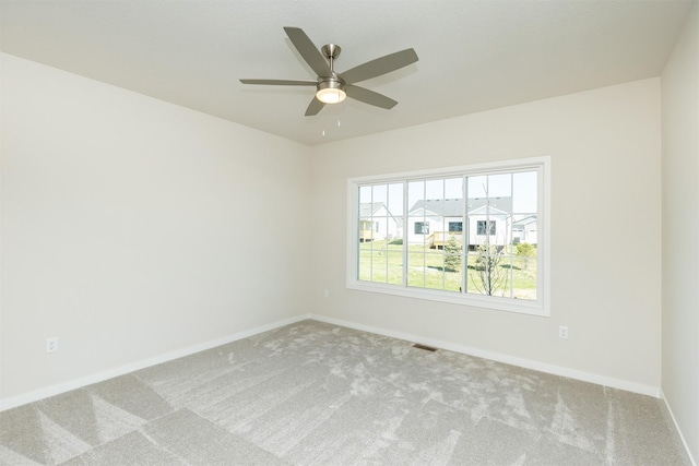 carpeted empty room with baseboards, a ceiling fan, and visible vents