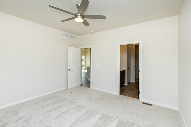 unfurnished bedroom with baseboards, visible vents, carpet floors, and ceiling fan