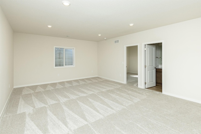 spare room featuring recessed lighting, light carpet, visible vents, and baseboards