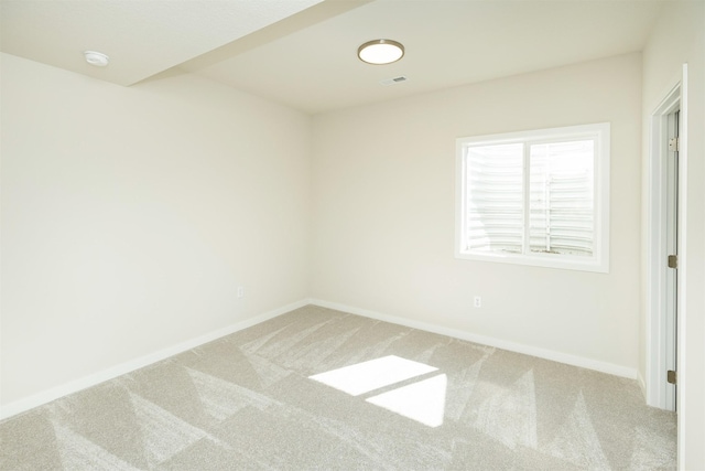spare room featuring visible vents, light carpet, and baseboards