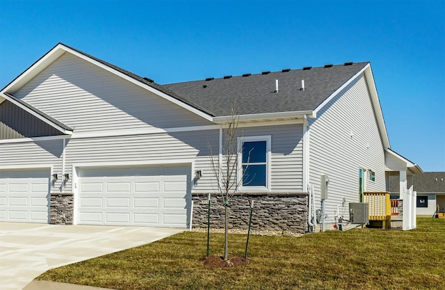 view of front of home with a front lawn, central air condition unit, stone siding, concrete driveway, and a garage