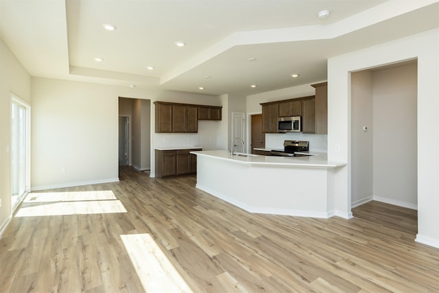 kitchen featuring decorative backsplash, stainless steel appliances, light wood-type flooring, and light countertops
