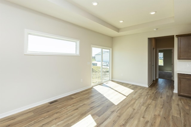 unfurnished room featuring light wood-style floors, visible vents, baseboards, and a healthy amount of sunlight