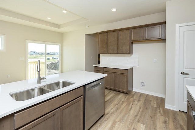 kitchen with dishwasher, a sink, light countertops, and light wood-style flooring