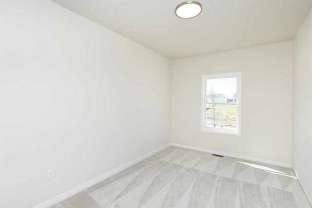 spare room with baseboards, visible vents, and light colored carpet