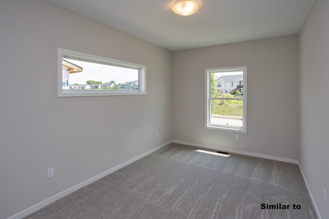 spare room with carpet floors, visible vents, and baseboards