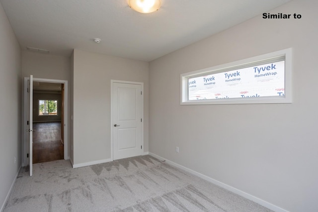 unfurnished bedroom with light colored carpet, visible vents, and baseboards