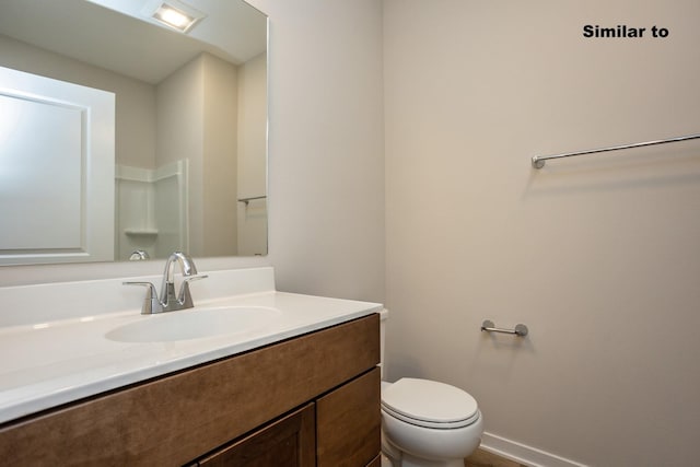 bathroom featuring baseboards, vanity, and toilet