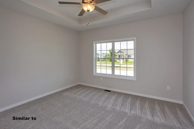 spare room with ceiling fan, carpet flooring, a raised ceiling, and baseboards