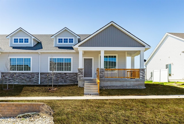 craftsman-style house featuring stone siding, a front lawn, and covered porch