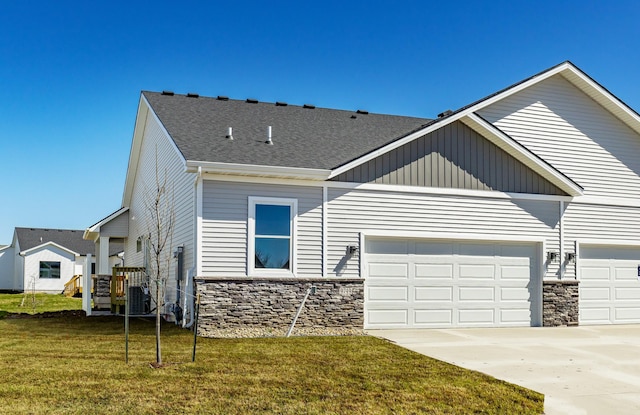 view of front of home with concrete driveway, stone siding, an attached garage, cooling unit, and a front yard