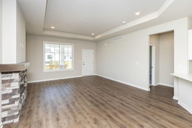 unfurnished living room featuring wood finished floors, a tray ceiling, baseboards, visible vents, and recessed lighting