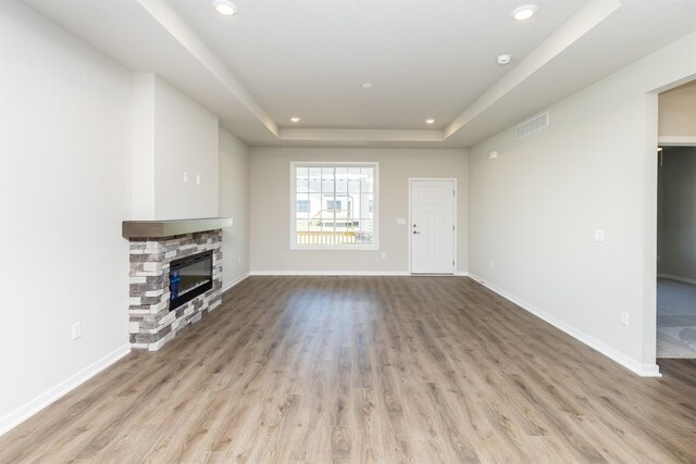 unfurnished living room with recessed lighting, wood finished floors, and a tray ceiling