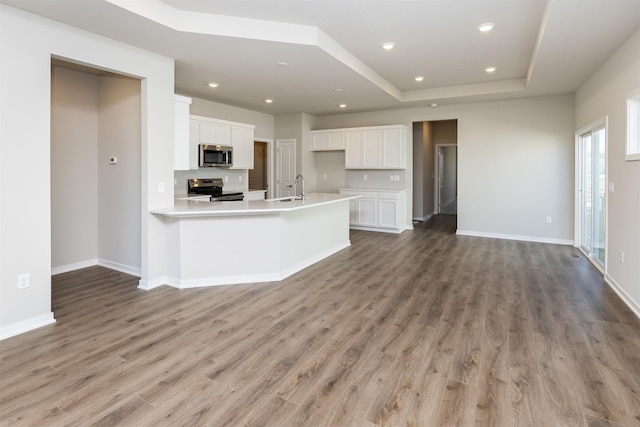 kitchen with a sink, light countertops, stainless steel appliances, light wood-style flooring, and white cabinets