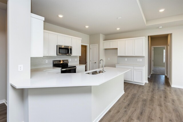 kitchen featuring a sink, light wood-style flooring, light countertops, baseboards, and appliances with stainless steel finishes